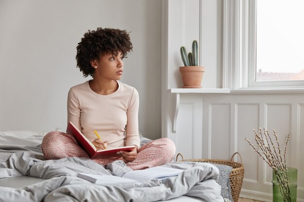 Schönes verträumtes hübsches Mädchen, das zu Hause im bequemen Bett aufwirft