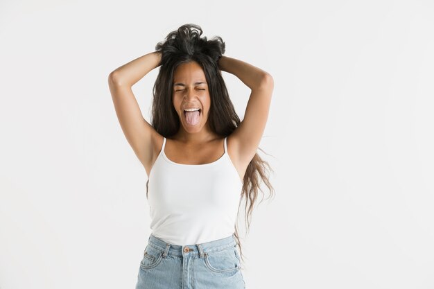 Schönes weibliches Porträt der halben Länge lokalisiert auf weißem Studiohintergrund. Junge emotionale Afroamerikanerfrau mit langen Haaren. Gesichtsausdruck, menschliches Gefühlskonzept. Fühlt sich verrückt glücklich, springend.