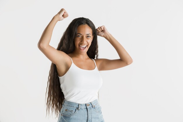 Schönes weibliches Porträt lokalisiert. Junge emotionale Afroamerikanerfrau mit langen Haaren. Gesichtsausdruck, menschliches Gefühlskonzept. Feiern und lächeln.