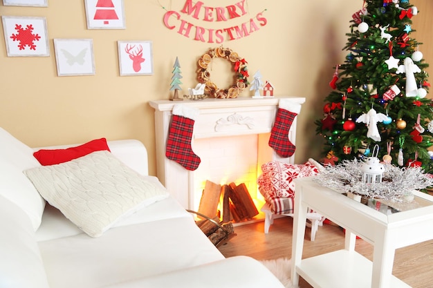 Schönes weihnachtsinterieur mit sofa, dekorativem kamin und tannenbaum