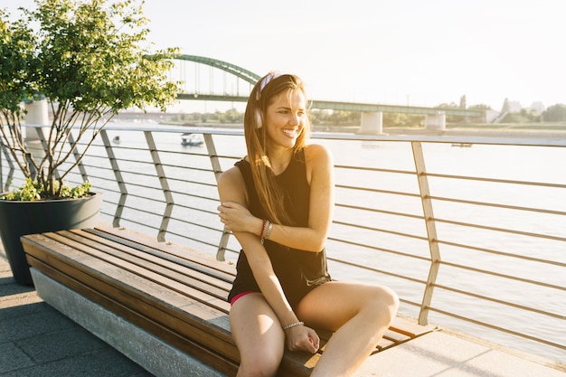 Schönheit, die den nahe gelegenen Fluss hört Musik sitzt