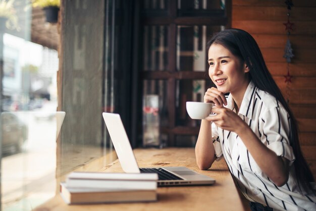 Schönheit, die mit Laptop-Computer am Kaffeestubecafé arbeitet