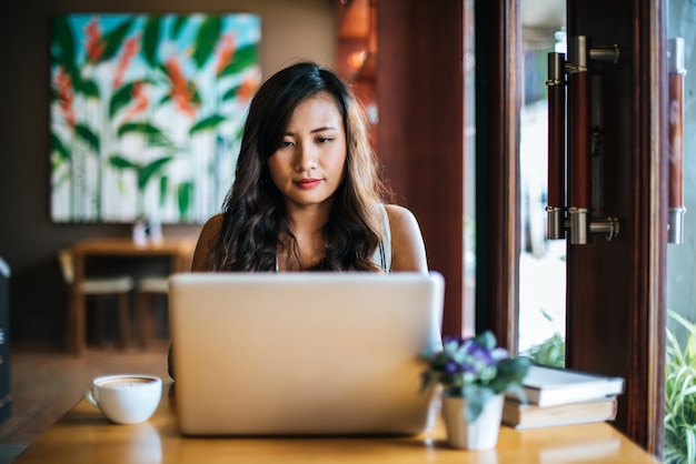 Schönheit, die mit Laptop-Computer am Kaffeestubecafé arbeitet