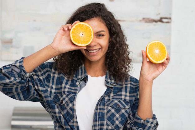 Schönheit, die Orangen nah an ihrem Gesicht hält