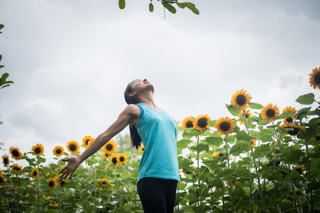 Schönheit mit dem Anheben der Hände auf einem Gebiet von Sonnenblumen im Sommer.