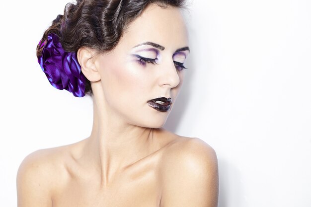 Schönheit und Gesundheit, Kosmetik und Make-up. Porträt des Modefrauenmodells mit hellem purpurrotem Make-up, gelockte Frisur auf hellem weißem Hintergrund.