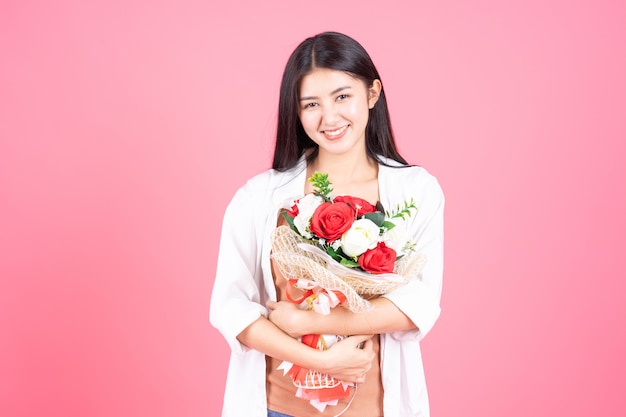 Schönheitsfrau Asiatisches nettes Mädchen fühlen sich glücklich, Blumenrotrose und -weißrose auf rosa Hintergrund halten