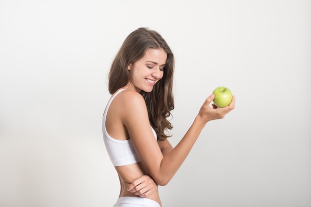 Schönheitsfrau, die grünen Apfel hält, während Sie auf Weiß lokalisiert werden