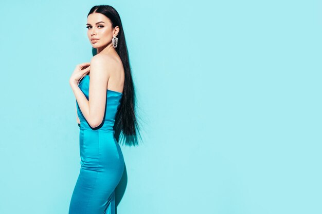 Schönheitsporträt der jungen Brunettefrau mit Abendmake-up und perfekter sauberer Haut Sexy Modell mit dem langen Haar, das im Studio lokalisiert im blauen Kleid aufwirft