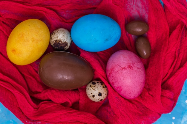 Kostenloses Foto schokolade und bunte ostereier auf rotem tuch