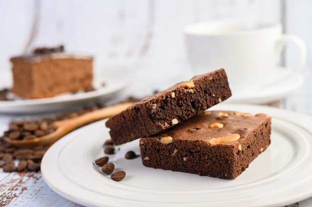 Schokoladen-Brownies auf einem weißen Teller und Kaffeebohnen auf einem Holzlöffel.