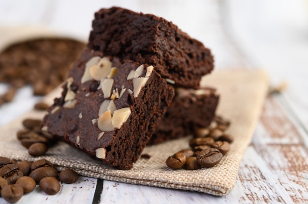 Schokoladen-Brownies auf Sackleinen und Kaffeebohnen auf einem Holztisch.