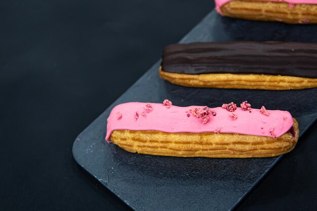 Schokoladen- und Beeren-Eclairs-Nahaufnahme auf schwarzem Hintergrund