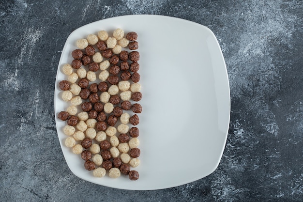 Schokoladen- und Weizenkugeln auf weißem Teller.