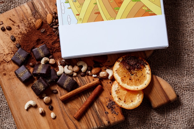 Schokoladenbonbons Zimtorange und Nüsse auf Holzschreibtisch.