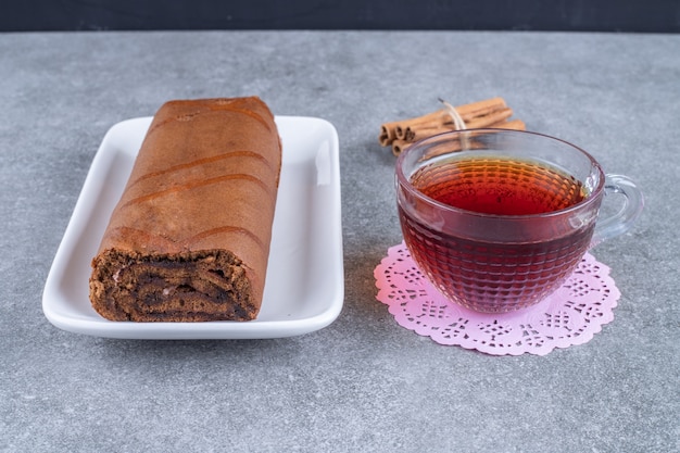 Schokoladenbrötchenkuchen und heißer Tee auf Marmoroberfläche