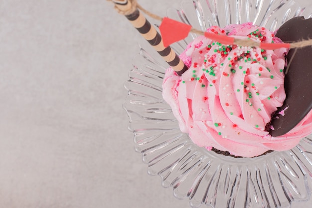 Schokoladencupcake mit Zuckerguss und Sprinklern auf Glas.