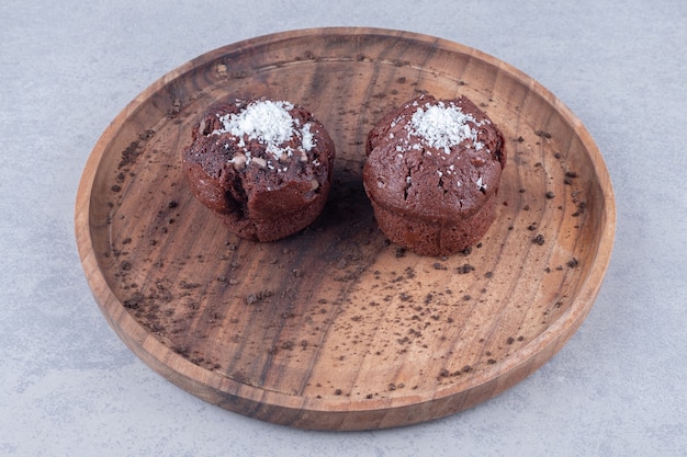 Schokoladencupcakes auf einem Holztablett auf Marmortisch.