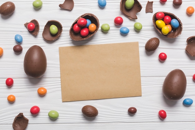 Schokoladeneier und Süßigkeiten um Papierblatt