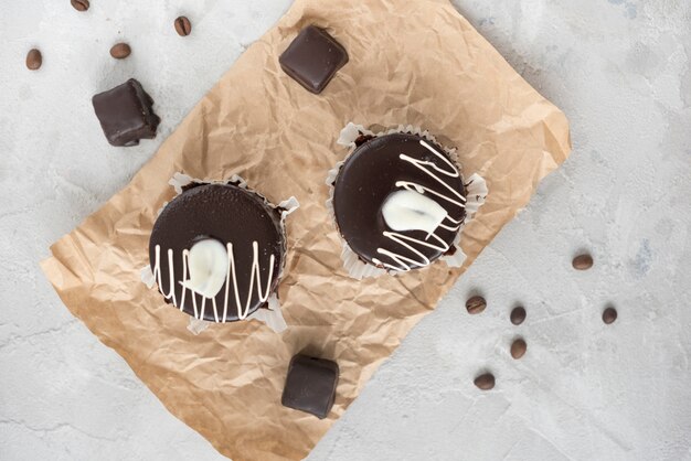 Schokoladenkleiner kuchen auf zerknittertem braunem Papier mit Kaffeebohnen