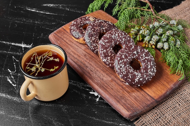 Schokoladenkrapfen auf einer Holzplatte mit Tee.