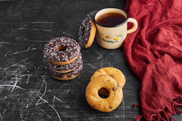 Schokoladenkrapfen und Kekse mit einer Tasse Tee.