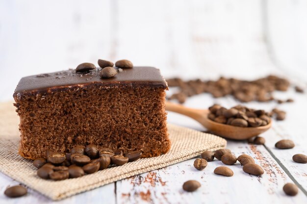 Schokoladenkuchen auf dem Sack mit Kaffeebohnen auf einem Holztisch.