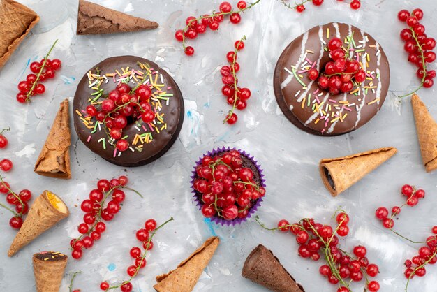 Schokoladenkuchen der Draufsicht mit Donuts, die mit Früchten und Hörnern auf dem weißen Hintergrundkuchen-Keks-Donutzucker entworfen wurden