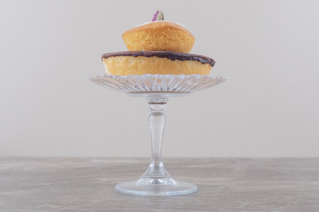 Schokoladenkuchen und Vanillepulver-Kuchen auf einem Glassockel auf Marmor gestapelt