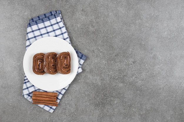 Schokoladenkuchenrolle auf weißem Teller mit Zimt