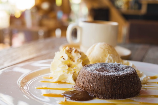 Schokoladenlavakuchen in der weißen platte mit kaffeetasse in der kaffeestube