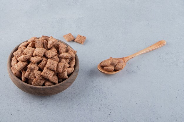 Schokoladenpads Cornflakes in Holzschale auf Steinhintergrund. Foto in hoher Qualität