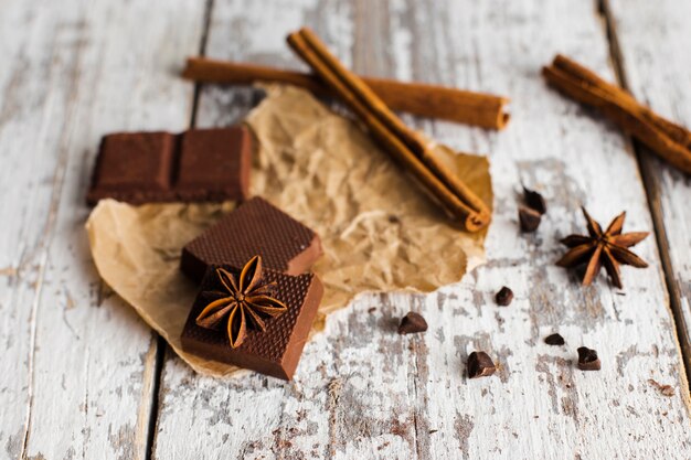 Schokoladenquadrate und Zimtstäbchen auf Papiertüten
