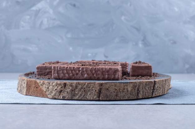 Schokoladenüberzogene Waffeln auf einem Holzbrett auf Marmor