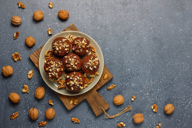 Schokoladenwalnussmuffins mit Kaffeetasse mit Walnüssen auf dunkler Oberfläche