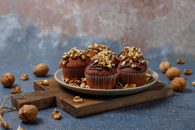 Schokoladenwalnussmuffins mit Kaffeetasse mit Walnüssen auf dunkler Oberfläche