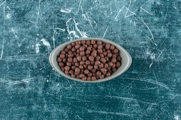 Schokoladenzuckermaisbällchen in einer Schüssel auf blauem Hintergrund. Foto in hoher Qualität