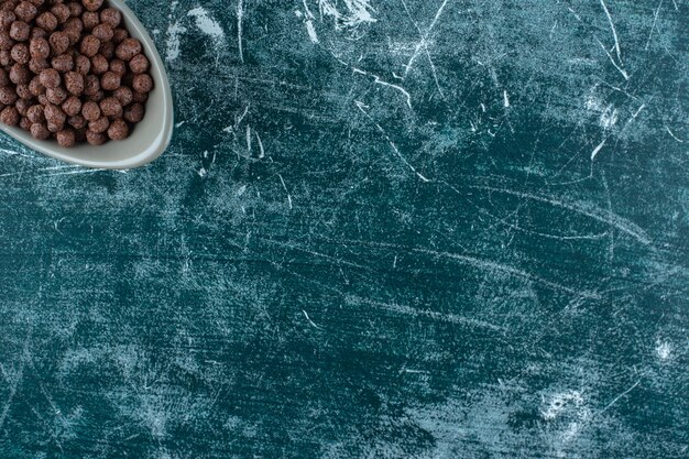 Schokoladenzuckermaisbällchen in einer Schüssel auf blauem Hintergrund. Foto in hoher Qualität