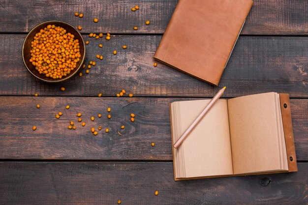 Schreibtisch Tisch mit Notizbüchern, frischen Sanddornbeeren auf Holztisch