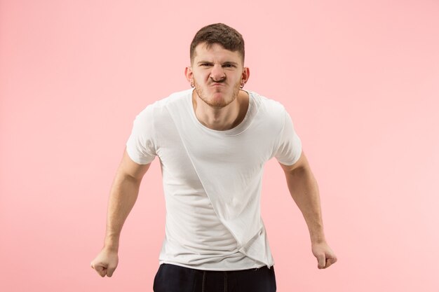 Schreien, Hass, Wut. Weinender emotionaler verärgerter Mann, der auf rosa Studiohintergrund schreit. Emotionales, junges Gesicht. männliches Porträt in halber Länge. Menschliche Emotionen, Gesichtsausdruckkonzept. Trendige Farben