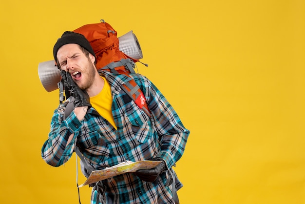 schreiender junger Rucksacktourist mit schwarzem Hut mit Karte