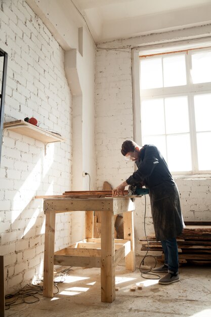 Schreiner mit Macht Hand sah Schneiden Holzbohlen in der Werkstatt