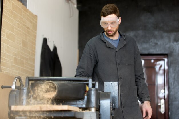 Schreinerei in Schutzbrille arbeitet auf Werkzeugmaschine