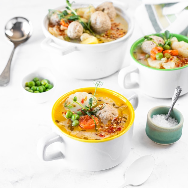 Schritt 4 Rezept für Suppe mit Fleischbällchen Blumenkohl Baby Erbsen Karotten und Sahne auf weißem Hintergrund Square