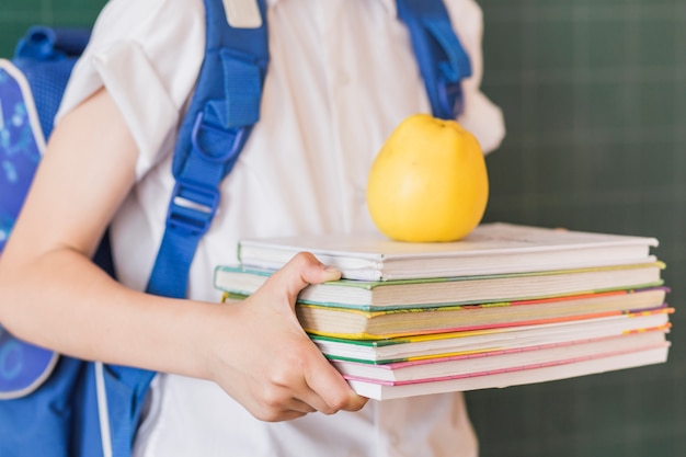 Schüler, der Lehrbücher und Apfel hält