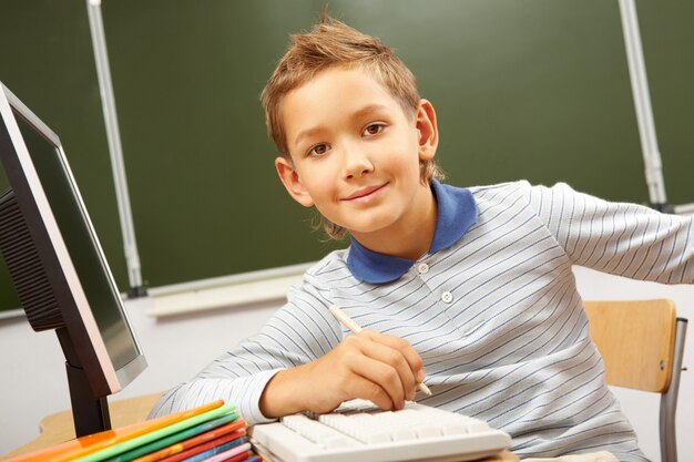 Schüler mit einem Bleistift der Nähe des Computers