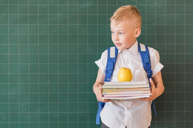 Schüler mit Rucksack und Lehrbüchern im Klassenzimmer