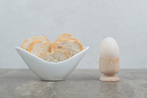 Schüssel Brotscheiben und Ei auf Marmortisch. Hochwertiges Foto