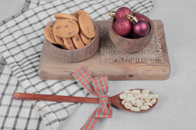 Schüssel Chipkekse und Weihnachtskugeln auf weißem Tisch. Hochwertiges Foto