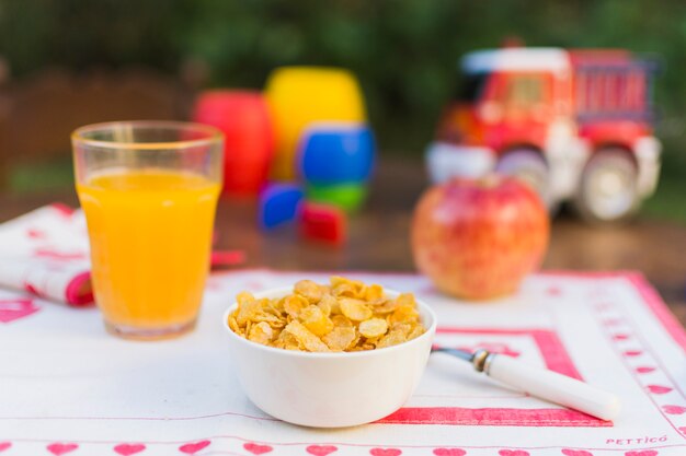 Schüssel Corn Flakes, Saft und Apfel auf Tabelle